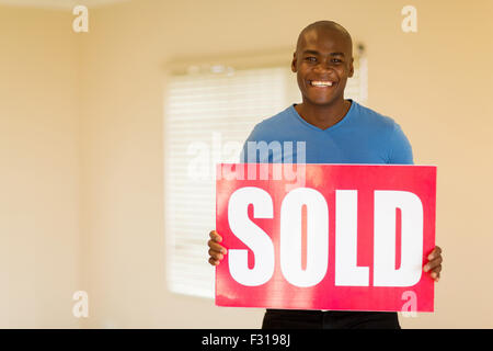 happy young black man holding sold sign in his home Stock Photo