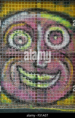 Ugly pink face. Colourful graffiti spray painted on a window shutter. Detail of urban street art by artist known as Loko. Montpellier, South of France. Stock Photo