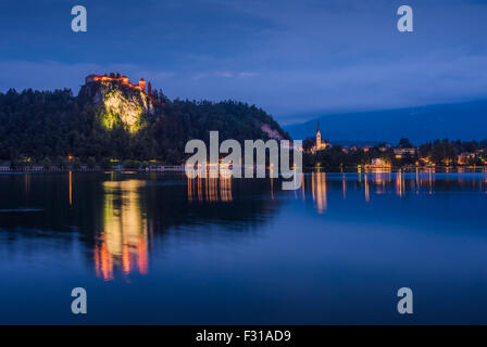 Illuminated Bled Castle at Bled Lake in Slovenia at Night Reflected on Water Surface Stock Photo