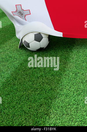 Soccer ball and national flag of Malta lies on the green grass Stock Photo