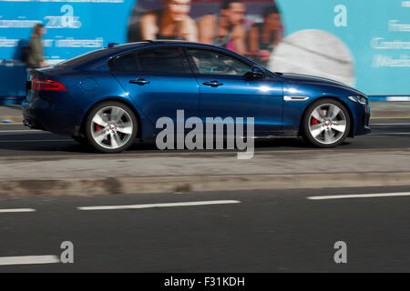 A blurred moving Jaguar XF at speed motion blur on 'The Strand' at Liverpool One, Liverpool, Merseyside, UK Stock Photo