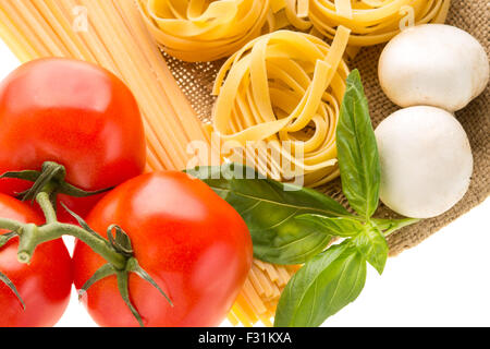 Spaghetti and nest pasta with mushrooms and branch of tomatoes. Ingredients for traditional past recipe background Stock Photo