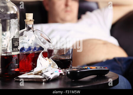 fat man lying on the couch watching tv Stock Photo