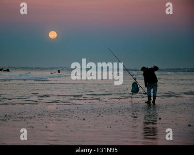 Brighton, UK.  28th September 2015. UK Weather. A fisherman on Brighton beach works as the supermoon sets behind him. The city hosts the third day of the Labour Party's annual conference today. (C) Paul Swinney/Alamy Live News Stock Photo