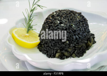 Black risotto and squid on the plate with lemon Stock Photo