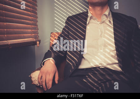 Young man is relaxing on an old sofa by the window on a sunny day Stock Photo