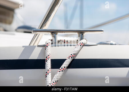 White mooring rope tied around steel anchor on boat Stock Photo