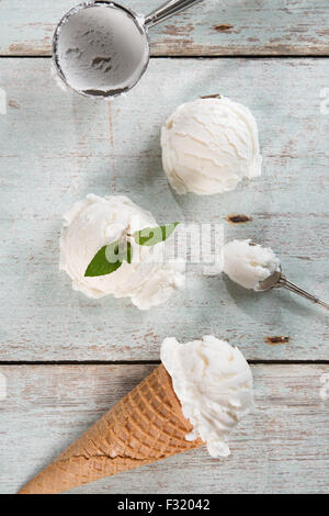 Top view vanilla ice cream in waffle cone with utensil on wood background. Stock Photo