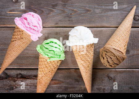 Chocolate, vanilla, matcha and strawberry ice cream in the cone on old rustic wooden vintage background. Stock Photo
