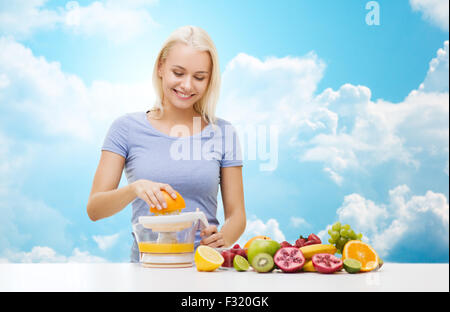smiling woman squeezing fruit juice over sky Stock Photo