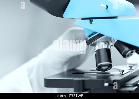 close up of scientist hand setting microscope Stock Photo