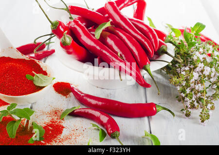 Red chili peppers with fresh herbs in  a white bowl. Selective focus Stock Photo