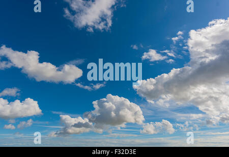 White fluffy cumulus clouds floating in a deep blue sky Stock Photo