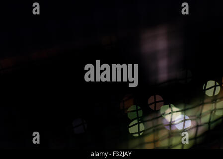 A dark abstract with colored balls of bokeh (out of focus light points) and a wavy wiring in front of them. Stock Photo