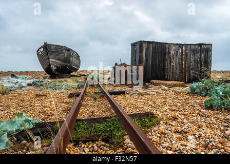 Abandoned fishing boat left to rot and decay on the beach at Dungeness, Kent. A grey, moody sky adds to the sad  scene Stock Photo