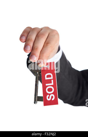 Realtor Holding Up Old Key with Red SOLD Sign on the white background Stock Photo