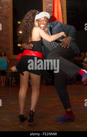 Semba dance show in a club, young couple dancing salsa. Kizomba dance performance. Smiling black man leading white woman Stock Photo