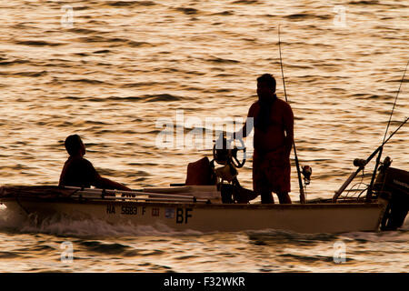 Silhouette of two fishermen in a boat at sunset hi-res stock