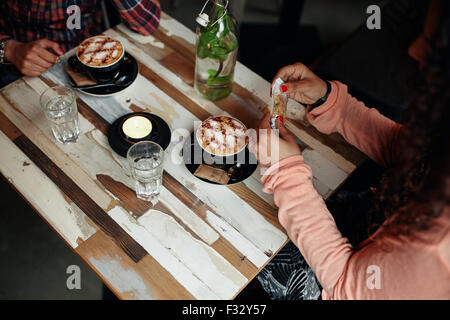 Directly above view of coffee on cafe table. Two women sitting at restaurant with cup of coffee.