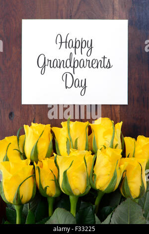 Yellow roses gift for Grandparents Day with greeting card on dark vintage wood table. Stock Photo