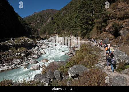 Travelers on path along Dudhkoshi river Nepal Stock Photo