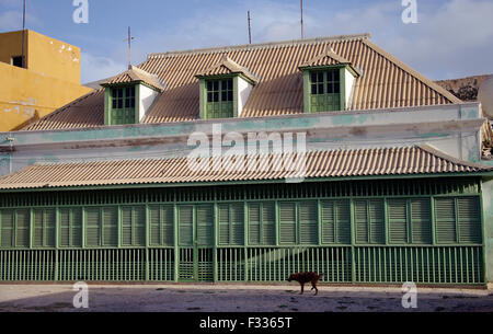 Large, ornate wooden house with long row of green shutters and a dog in front in Boa Vista on the island republic of Cape Verde Stock Photo