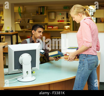 Employee scanning books in library at counter Stock Photo