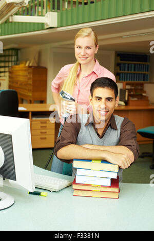 Two employees in a library at checkout counter Stock Photo