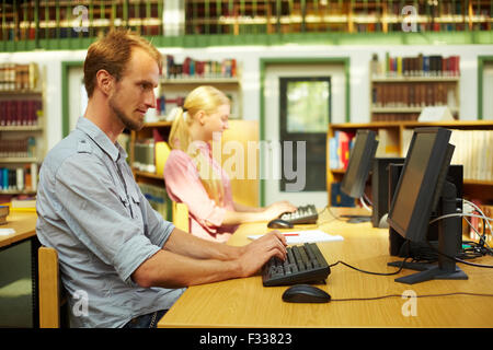 Students sitting in library and using computers Stock Photo