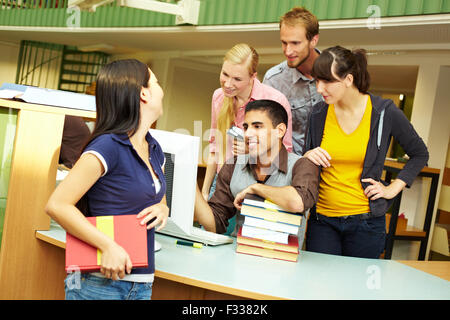 Library staff helping a student at counter Stock Photo