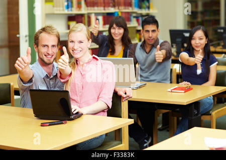 Five students holding their thumbs up in library Stock Photo