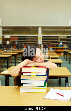 Student sleeping in library on stack of books Stock Photo