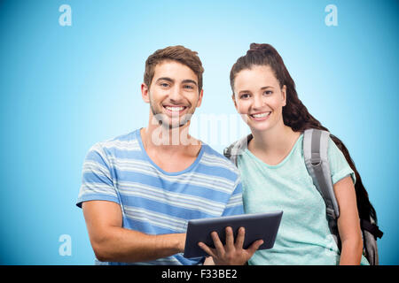 Composite image of students using tablet and smiling Stock Photo