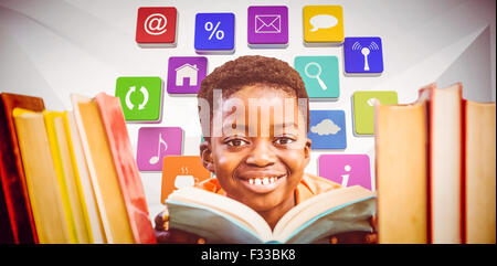 Composite image of cute boy reading book in library Stock Photo