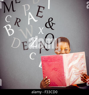 Composite image of cute boy reading book in library Stock Photo