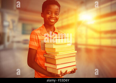 Composite image of portrait of cute boy carrying books in library Stock Photo