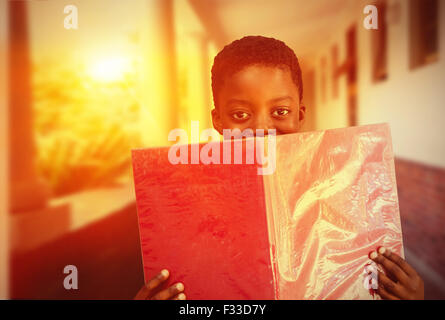 Composite image of cute boy reading book in library Stock Photo