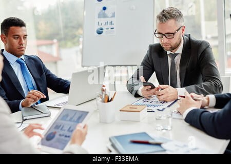 Businessmen using modern gadgets at meeting Stock Photo