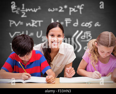 Composite image of pretty teacher helping pupils in library Stock Photo