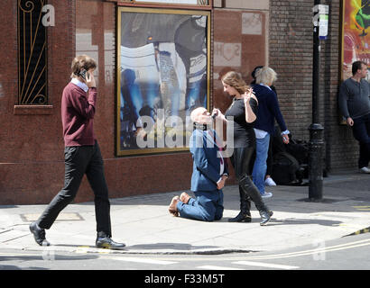 A man being publicly humiliated by a dominatrix in the streets of Soho