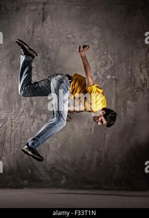 Young man jumping against grunge wall Stock Photo