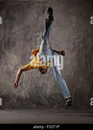 Young man jumping against grunge wall Stock Photo
