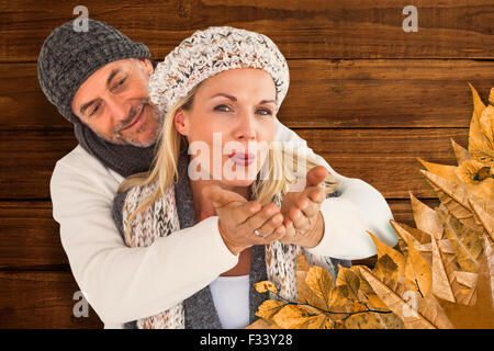 Composite image of husband hugging wife from behind as she blows kiss in air Stock Photo