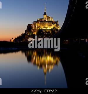A colour image of reflections of Mont Saint Michel lit up at dusk in a water pool on the beach at Mont Saint Michel Stock Photo