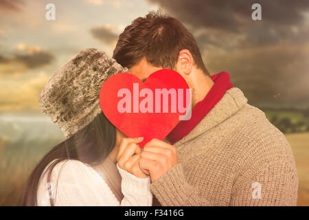 Young couple kissing behind a red heart isolated against white ...