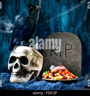 a plate with Halloween candies and an amputated finger in a dismal scene with a crow, a skull and a gravestone with the text RIP Stock Photo