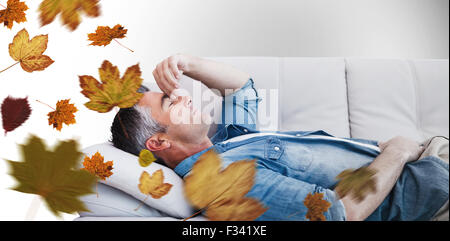 Composite image of man suffering from headache while on sofa Stock Photo