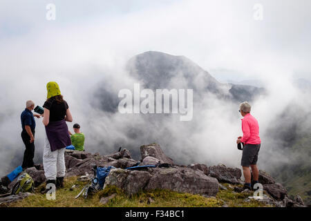 Hikers resting on Beenkeragh looking at view to Carrauntoohil through ...