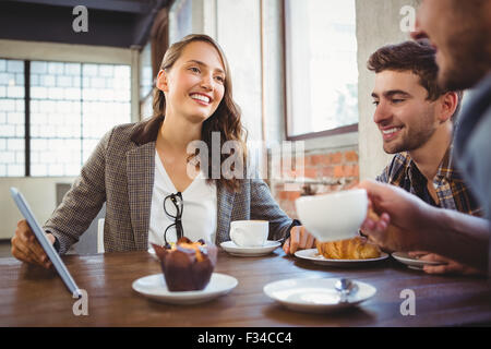 Smiling friends enjoying coffee and using at tablet Stock Photo