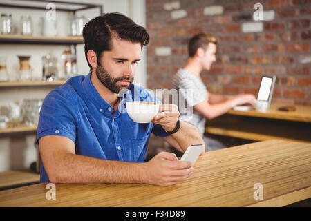 Young man enjoying a coffee and using his smartphone Stock Photo